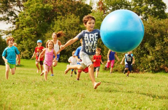 Un groupe d'enfants participant à une activité sportive, courant avec une grosse balle bleue.