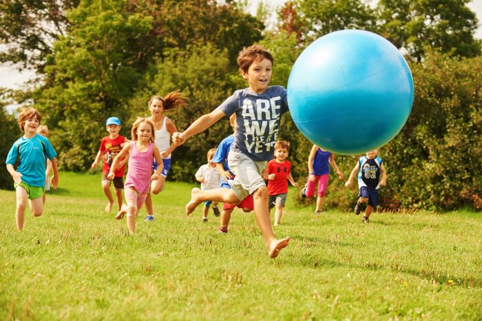 Un groupe d'enfants participant à une activité sportive, courant avec une grosse balle bleue.