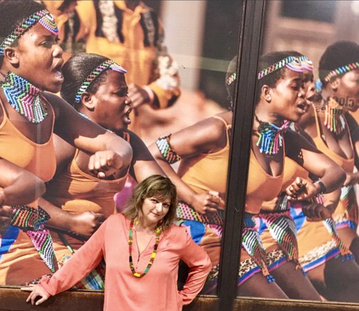 Une femme posant devant une grande affiche de danseurs africains dans Afrique du sud.