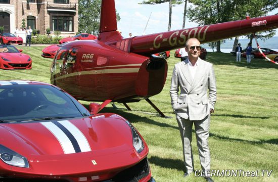 Un homme debout à côté d’une voiture de sport Ferrari rouge.
