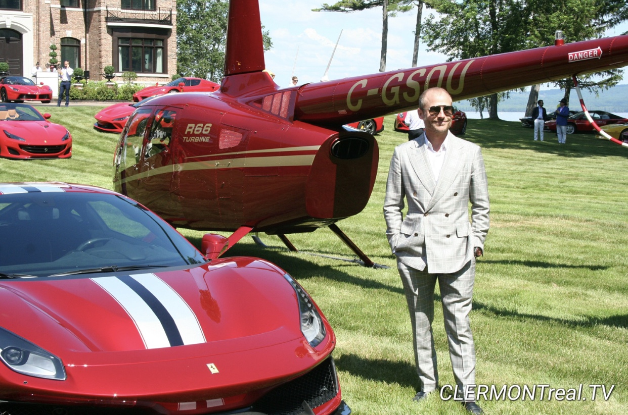 Un homme debout à côté d’une voiture de sport Ferrari rouge.