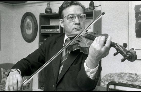 Une vieille photo en noir et blanc de Jean Carignan, un violoneux, jouant du violon.