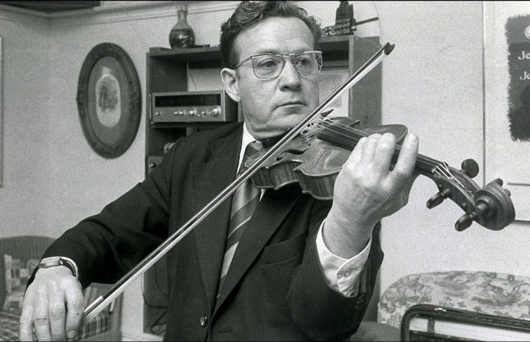 Une vieille photo en noir et blanc de Jean Carignan, un violoneux, jouant du violon.