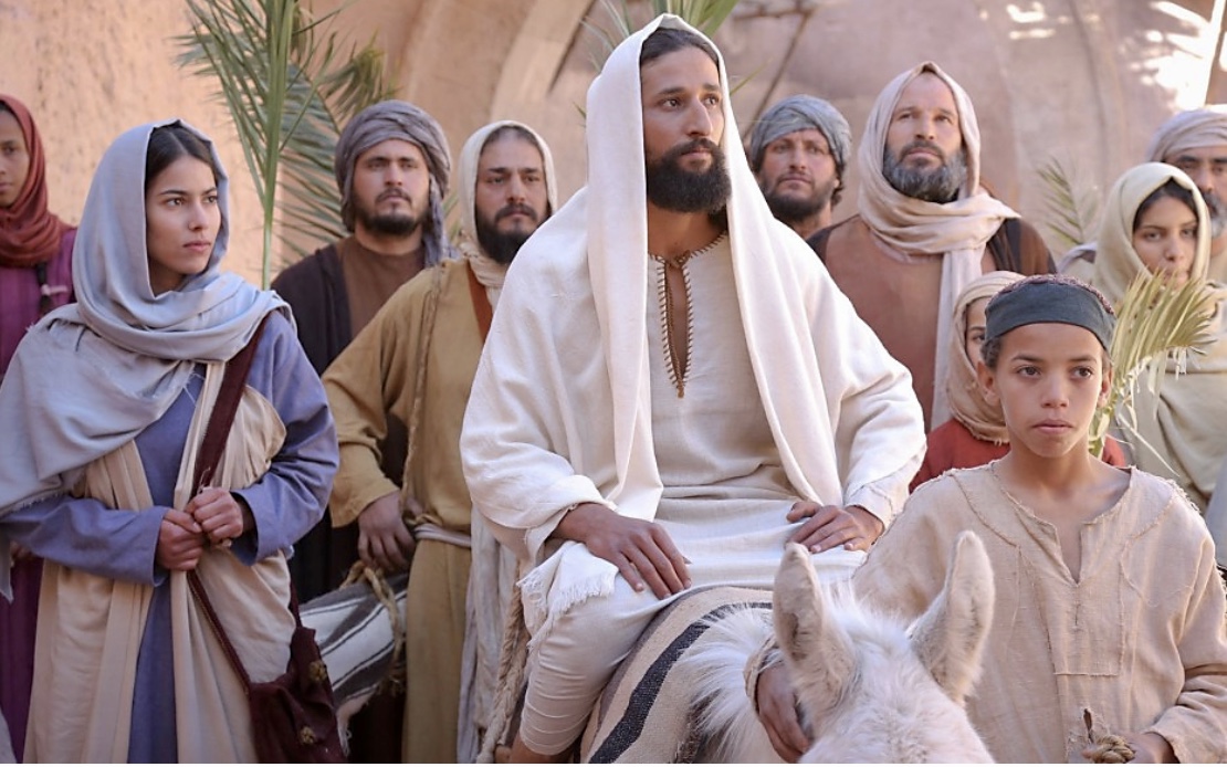 Un groupe de personnes engagées dans une philosophie spirituelle avec Jésus sur un âne.