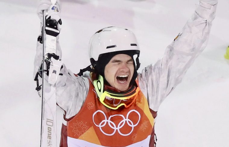 Un homme portant un casque tenant un ski et souriant aux activités sportives en 2020.
