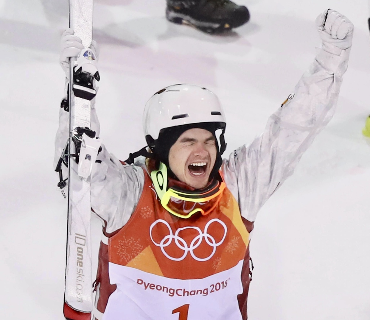 Un homme portant un casque tenant un ski et souriant aux activités sportives en 2020.