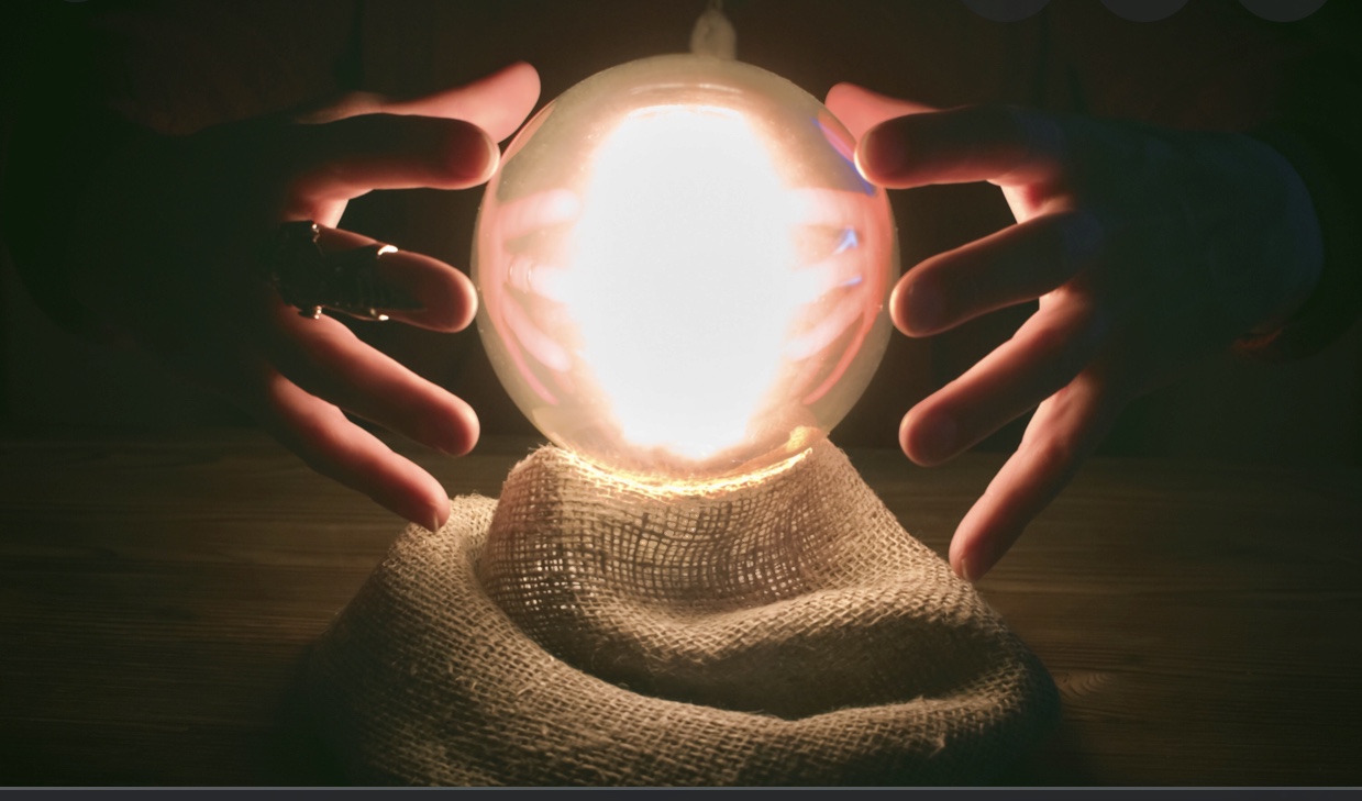 Une personne tient avec humour une boule de cristal lumineuse dans ses mains.
