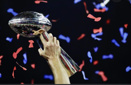 Une personne tient le trophée du Super Bowl au milieu d’une rafale de confettis.