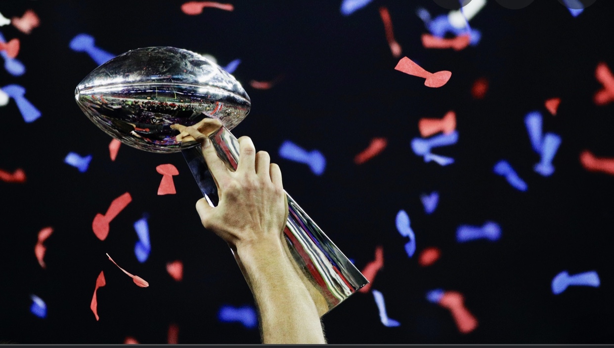 Une personne tient le trophée du Super Bowl au milieu d’une rafale de confettis.