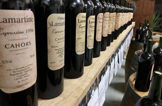 Plusieurs bouteilles de vin du Château LaMartine sont alignées sur une étagère pour dégustation.