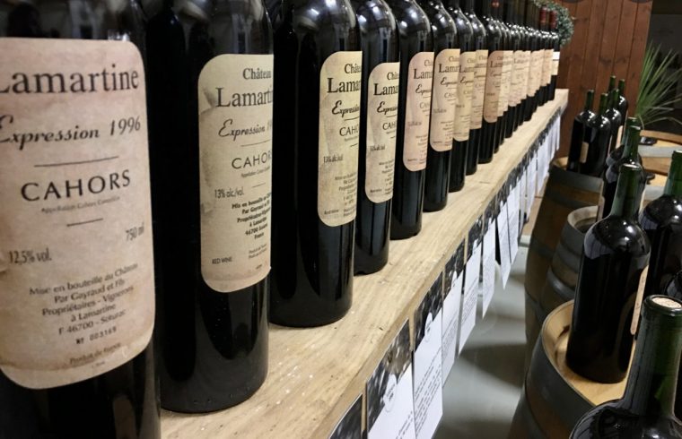 Plusieurs bouteilles de vin du Château LaMartine sont alignées sur une étagère pour dégustation.