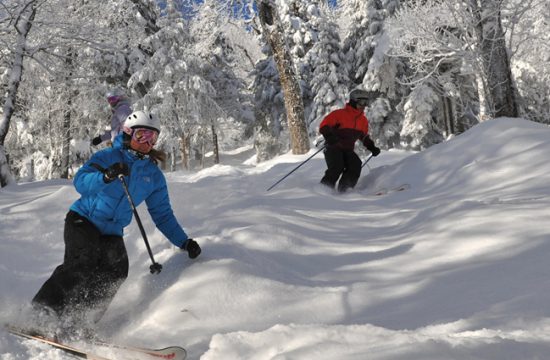 Deux personnes dévalent une colline enneigée en ski, avec une lueur d'espoir illuminant leur parcours.