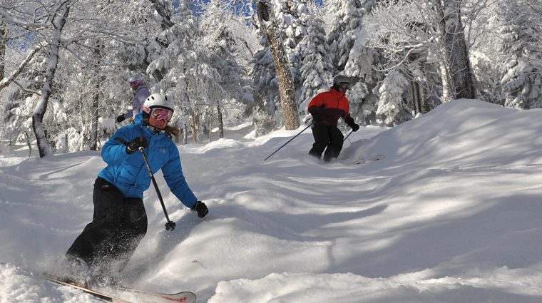 Deux personnes dévalent une colline enneigée en ski, avec une lueur d'espoir illuminant leur parcours.