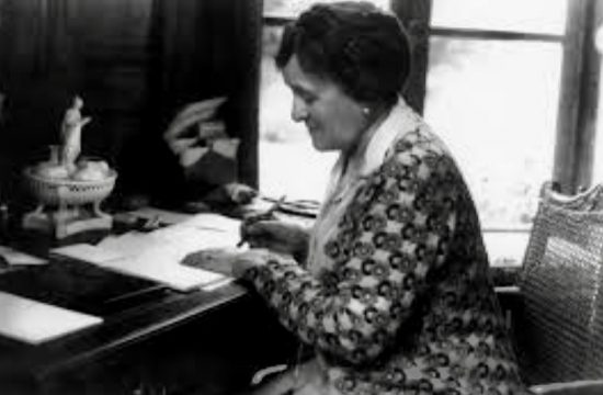 Une vieille photo d’une femme écrivant à un bureau, mettant en valeur l’importance des Droits des femmes.