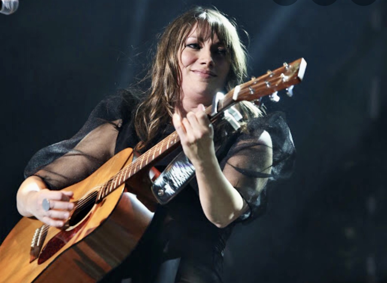 Une femme jouant de la guitare acoustique sur scène à l'Isle-aux-Coudres.