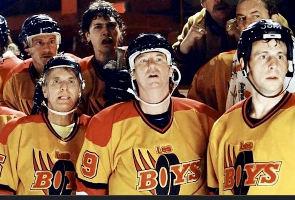 Un groupe de joueurs de hockey se tiennent côte à côte dans un cadre sportif.