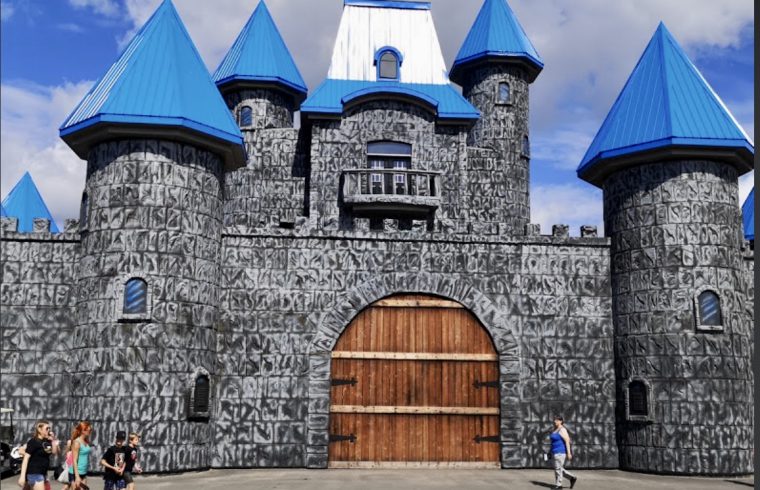 Un Parc d'attractions avec un château au toit bleu et aux tourelles.