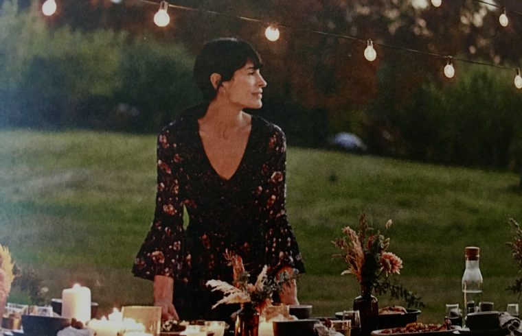Une femme se tient devant une table décorée de guirlandes lumineuses, présentant sa création culinaire.