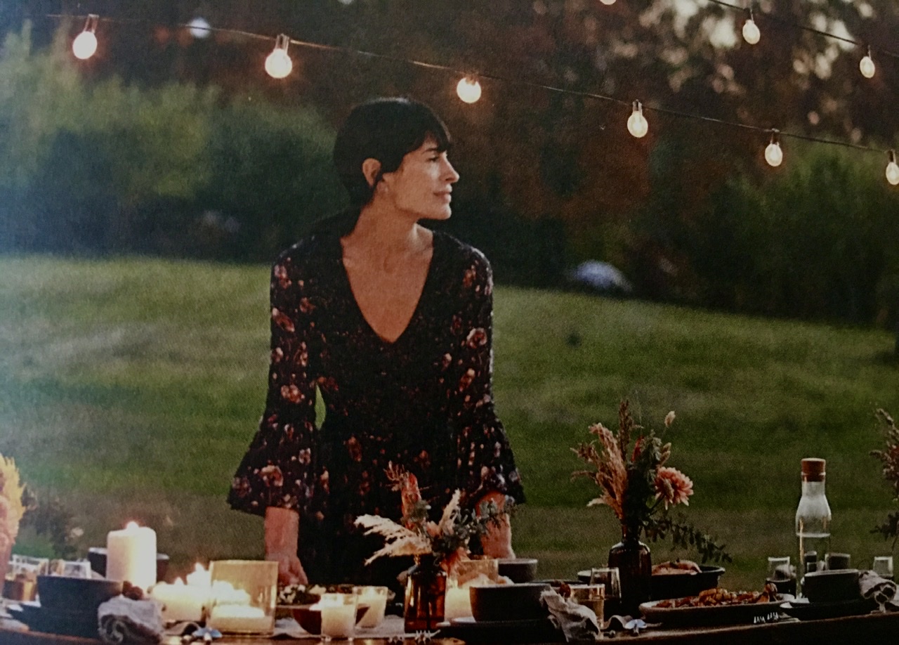 Une femme se tient devant une table décorée de guirlandes lumineuses, présentant sa création culinaire.