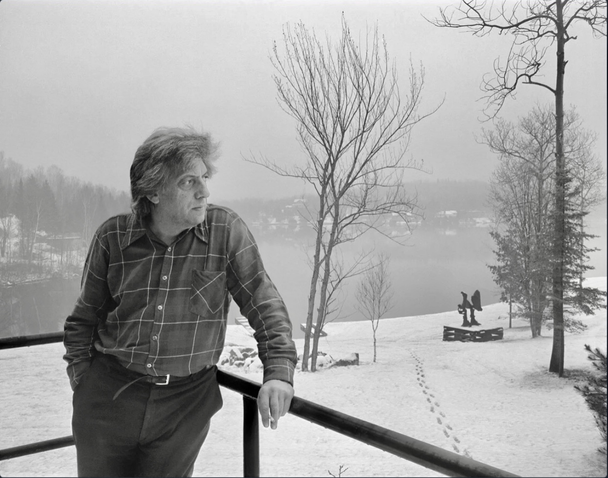 Un homme debout sur une balustrade près d’un lac sur une photo en noir et blanc.