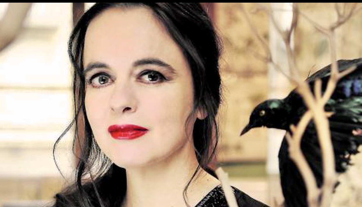 Une femme avec des cheveux noirs et du rouge à lèvres est debout à côté d'un oiseau.