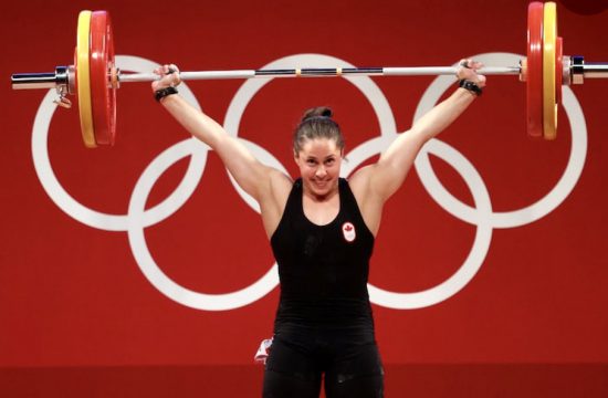 Une femme soulevant une barre devant un panneau olympique représentant la force et le dévouement des athlètes du monde entier.