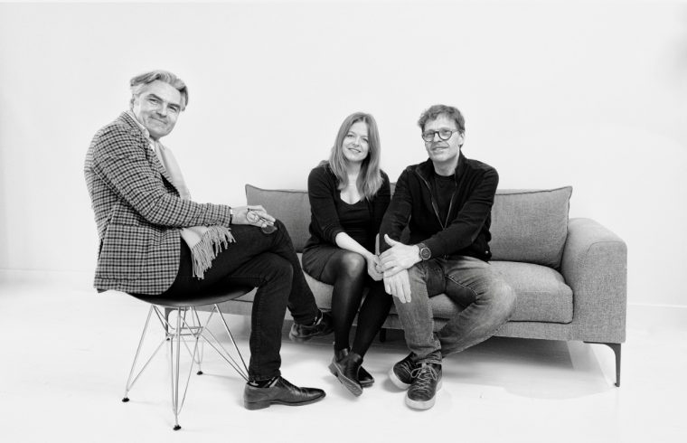Trois personnes assises sur un canapé sur une photo en noir et blanc représentant la Littérature québécoise.