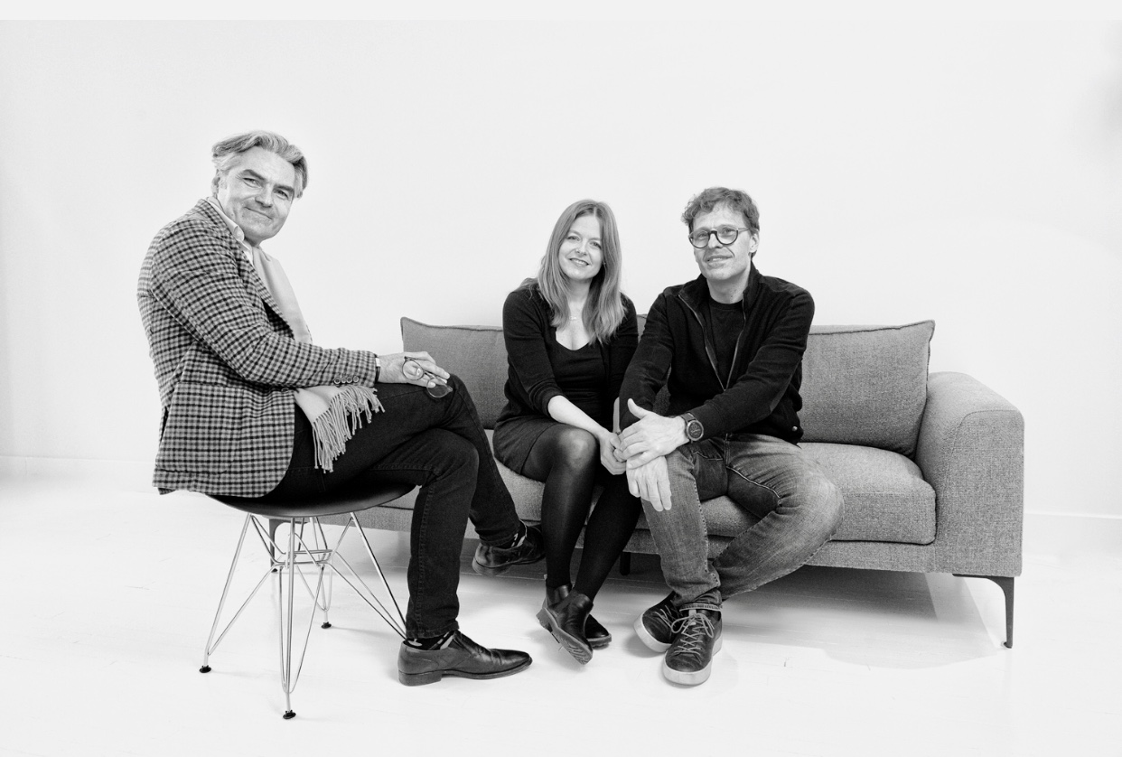 Trois personnes assises sur un canapé sur une photo en noir et blanc représentant la Littérature québécoise.