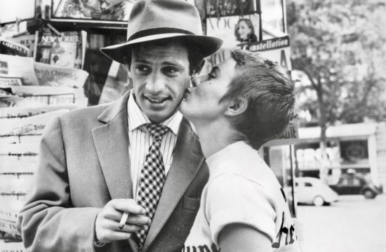 Jean-Paul Belmondo, coiffé d'un chapeau, embrasse affectueusement une femme au chapeau.