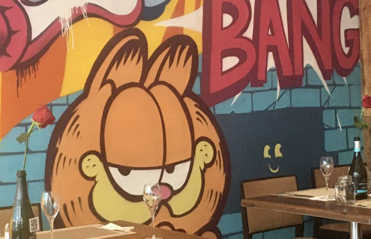 Un café à Montréal avec une murale Garfield au mur.