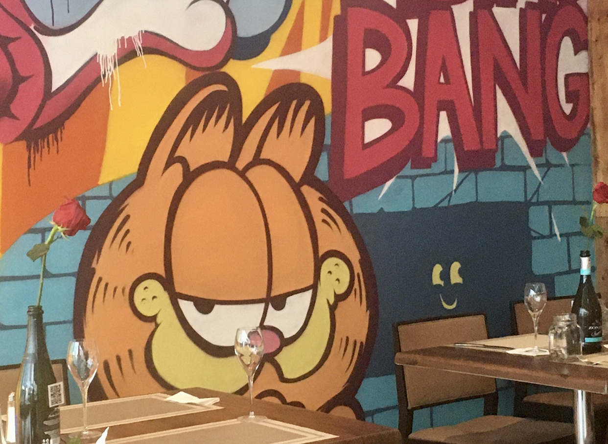 Un café à Montréal avec une murale Garfield au mur.
