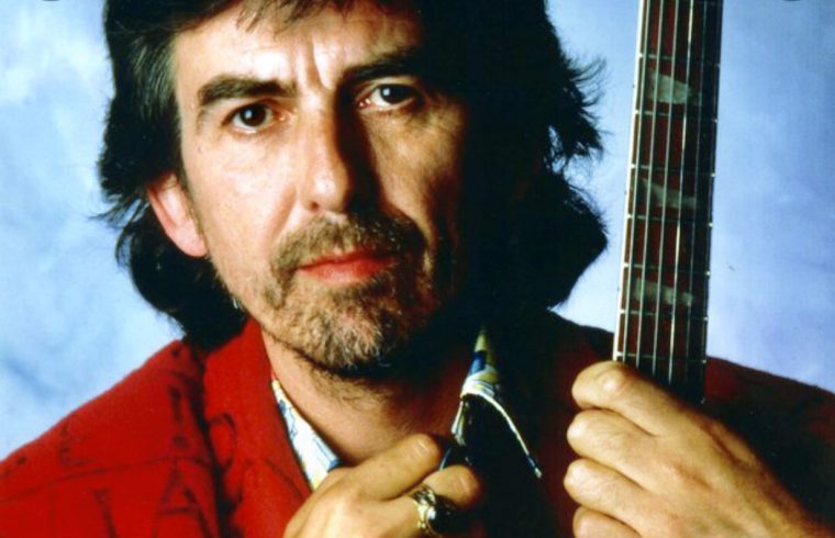 George Harrison tenant une guitare devant un ciel bleu.