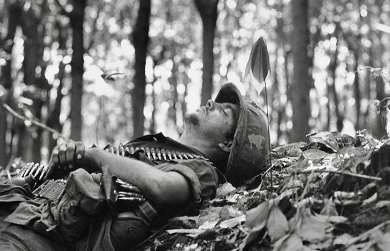 Un soldat plongé dans la philosophie, allongé dans les bois avec un fusil.