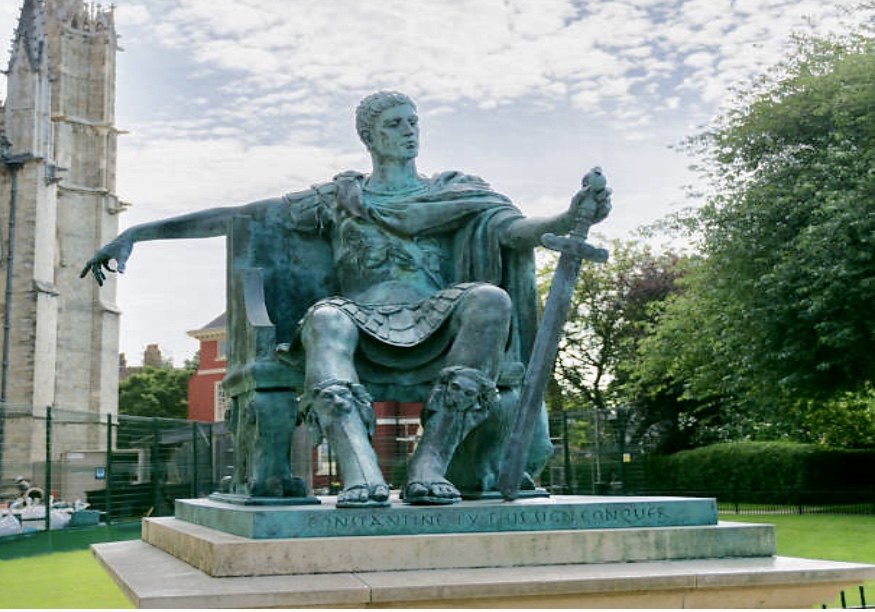 Une statue de Philosophie assise sur un banc devant une église.
