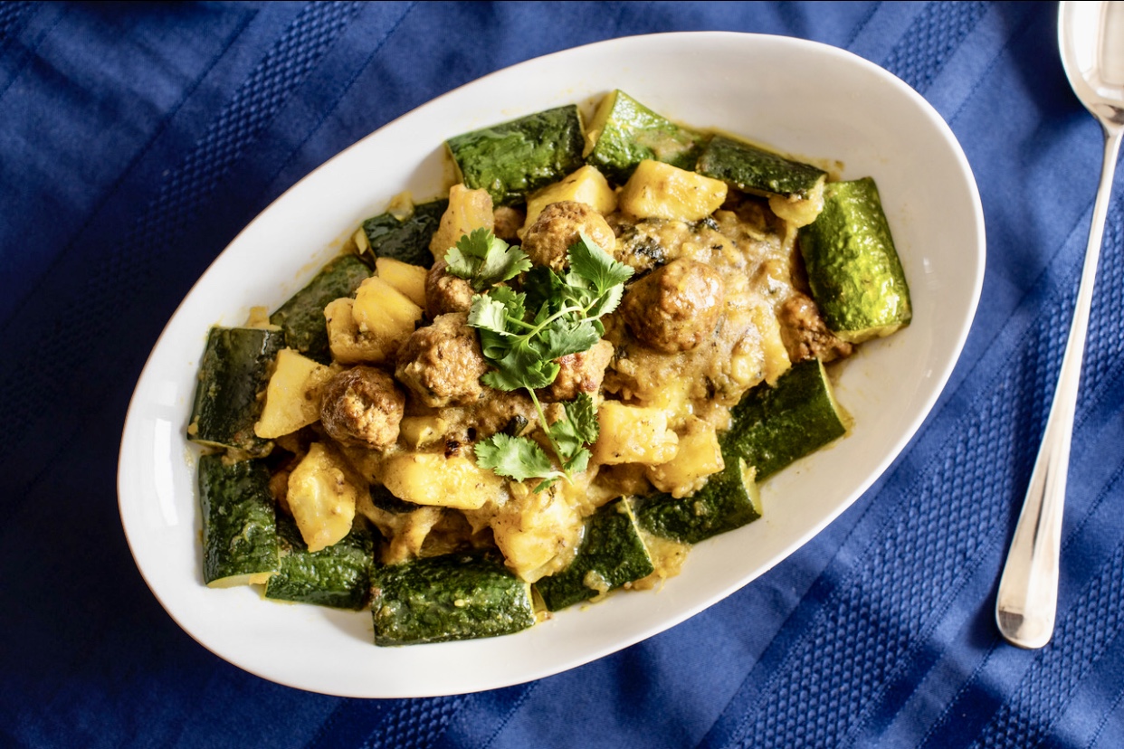 Un délicieux bol de curry avec de la viande tendre et des légumes vibrants sur une nappe bleue invitante.