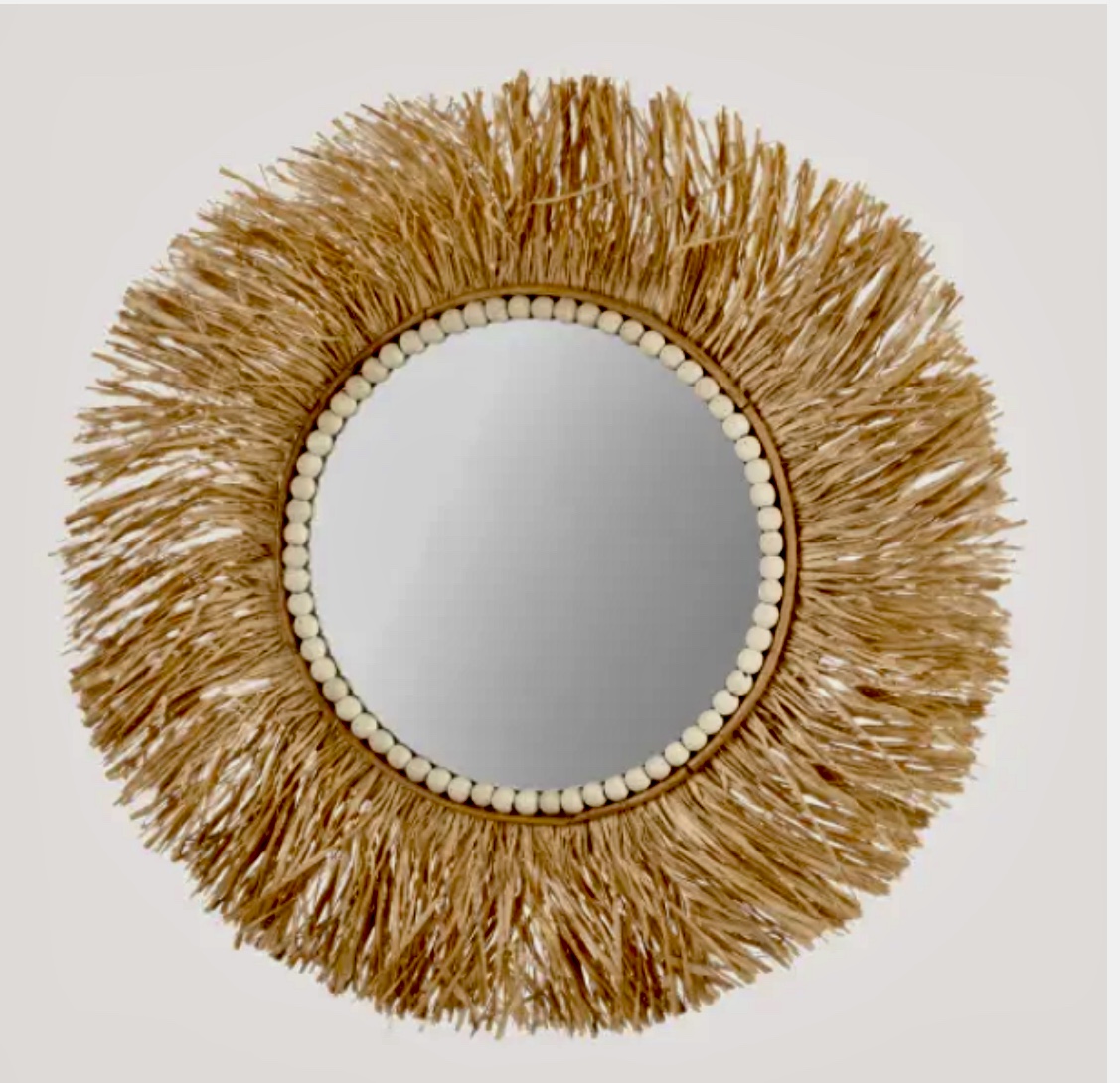 Un miroir rond joliment décoré avec une frange perlée, ajoutant une touche d'élégance à n'importe quel espace.