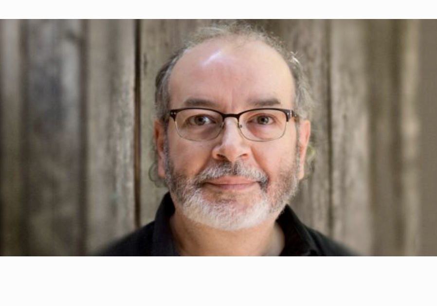 Un homme avec des lunettes et une barbe pose pour une photo à thème littéraire.