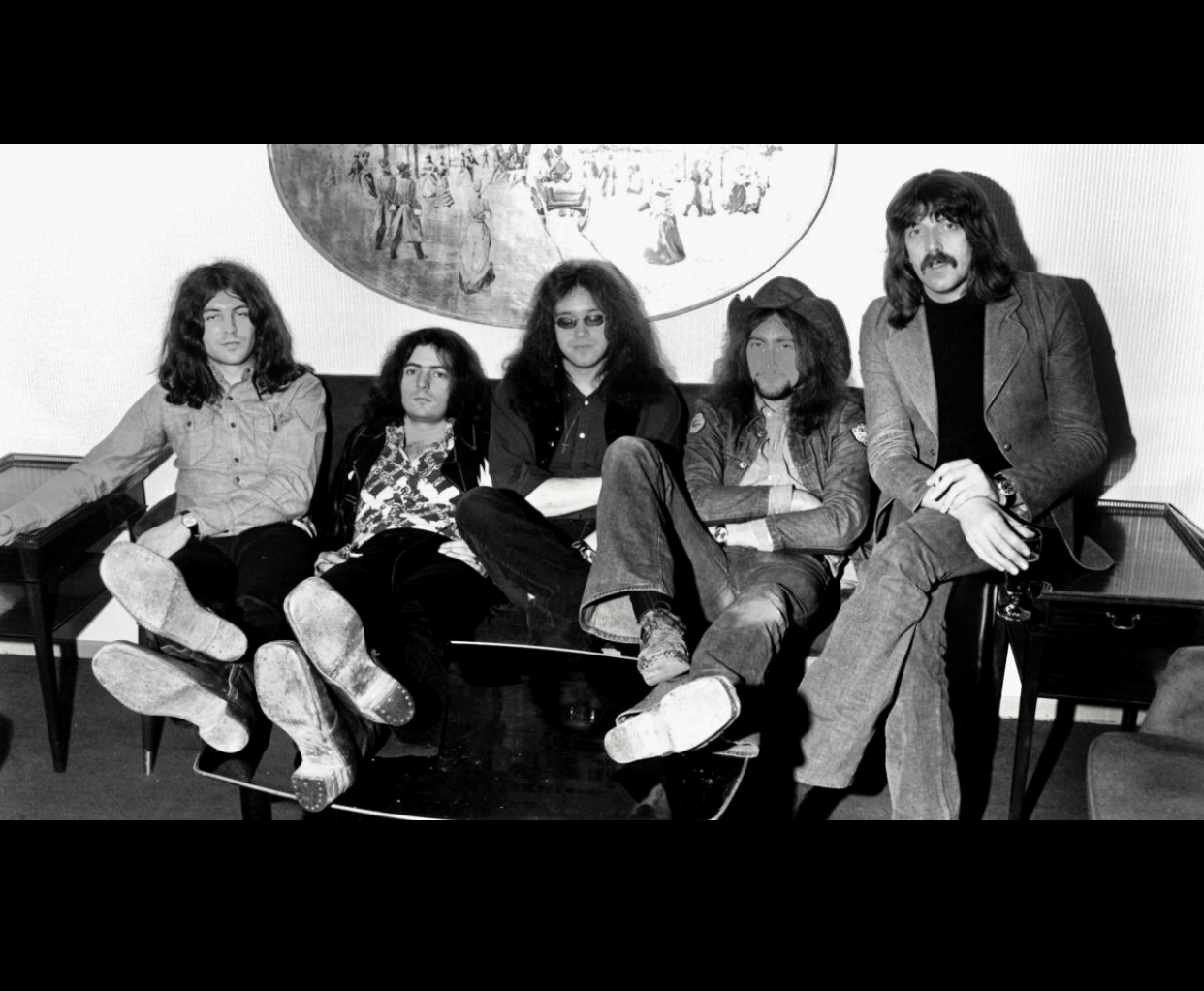 Une photo en noir et blanc d’un groupe de personnes assises sur un canapé, avec une touche de Deep Purple.