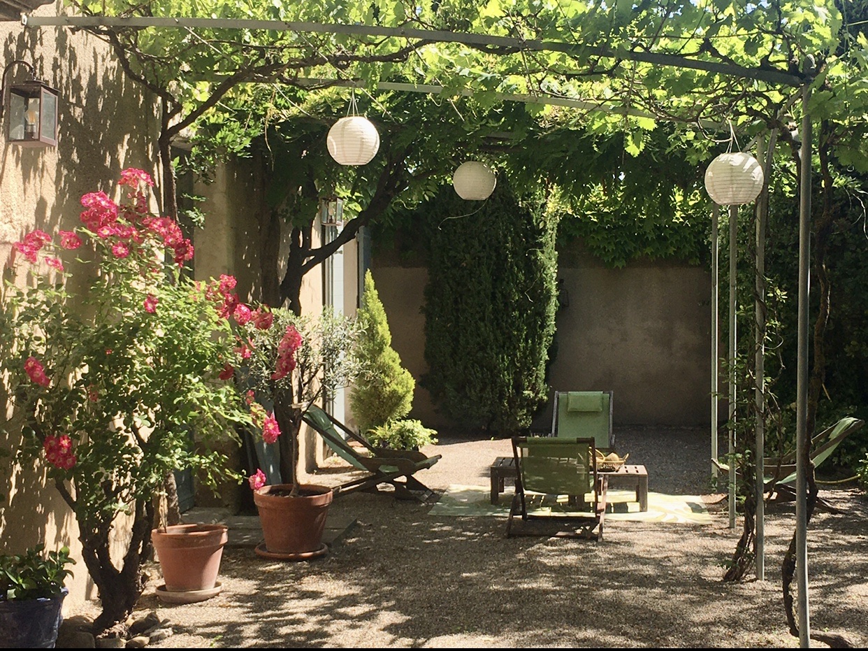 Avignon, sous le charme ! Un patio dans cette cour enchanteresse vous invite à vous détendre sur des chaises confortables au milieu d'une gamme vibrante de plantes en pot.