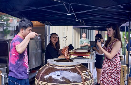 Un groupe de personnes debout autour d’une grande marmite de nourriture dans le Quartier chinois.