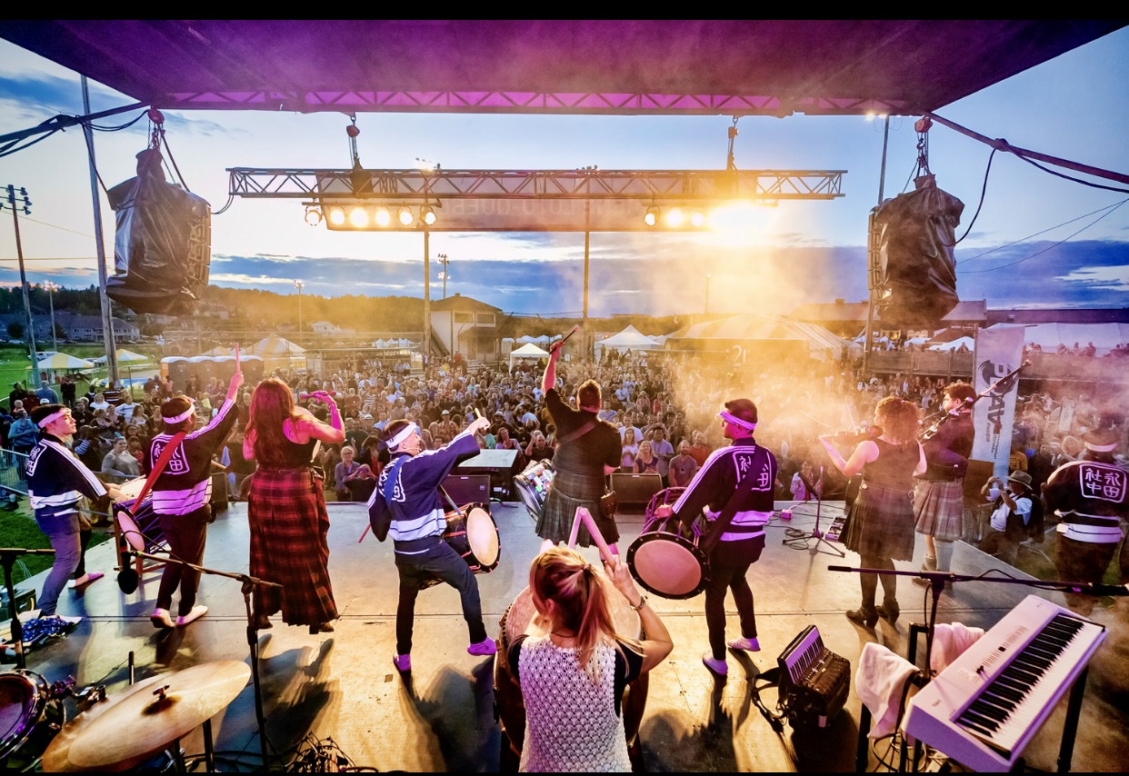 Un groupe de personnes sur scène lors d'un concert en plein air à Montréal.