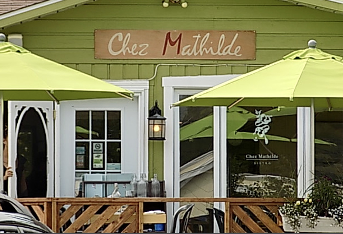 Un restaurant devant des parasols verts, proposant de délicieuses spécialités de Recettes Côte-Nord.