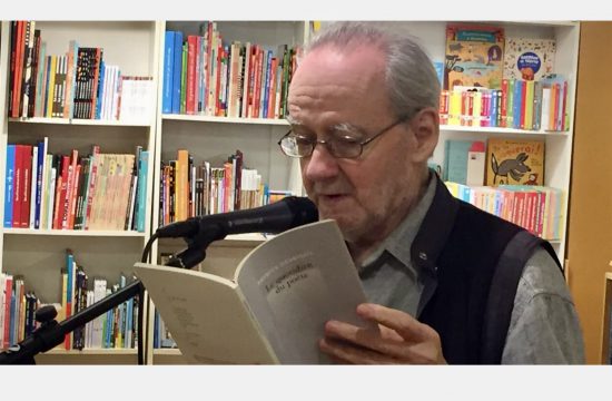 Un homme plus âgé, absorbé par la littérature, lisant un livre devant une étagère.