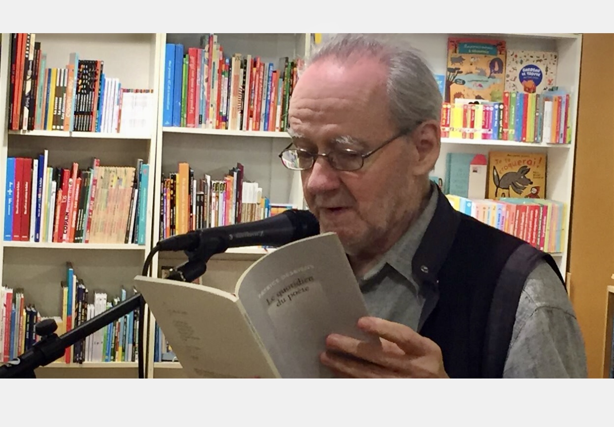 Un homme plus âgé, absorbé par la littérature, lisant un livre devant une étagère.