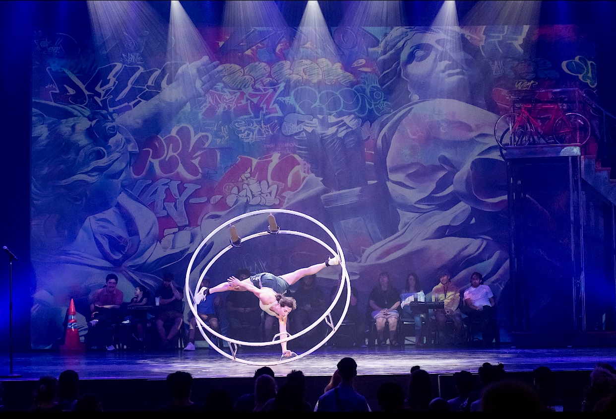 Une personne faisant un hula hoop devant une scène.