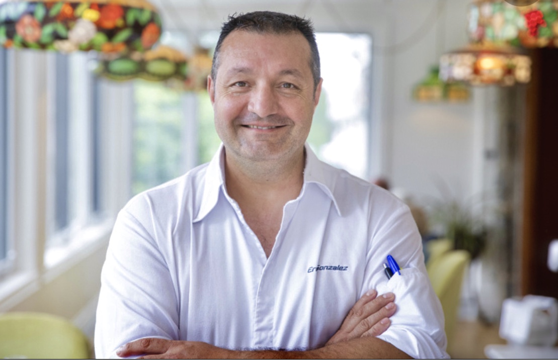 Un homme en chemise blanche mettant en valeur l'art de la Gastronomie québécoise, les bras croisés.