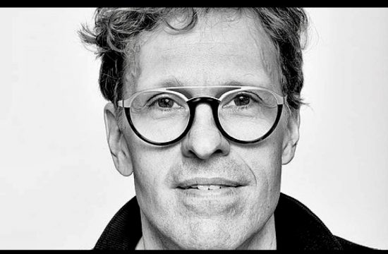 Une photo en noir et blanc d'un homme à lunettes, évoquant une ambiance littéraire.