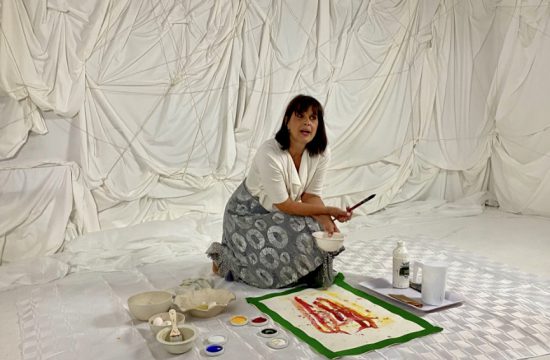 Une femme assise par terre avec un pinceau. (Arts visuels)