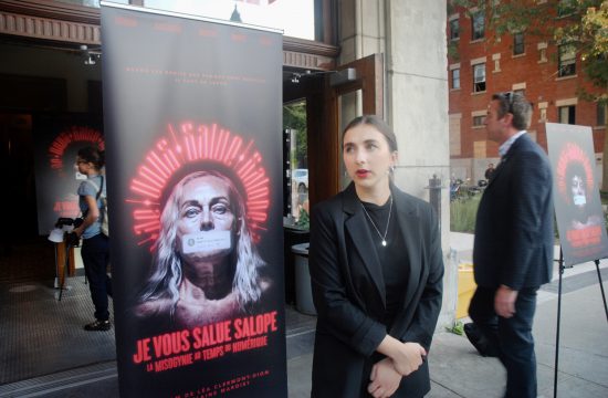 Une femme debout, confiante, devant une affiche pour Saint-Sulpice, indifférente à la violence ambiante.