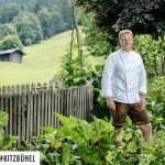 Un homme en chemise blanche debout dans un jardin suisse.